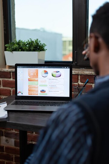 shoulder-view-startup-employee-analyzing-business-key-performance-indicators-laptop-screen-sitting-desk-close-focus-portable-computer-display-with-sales-results_482257-31286